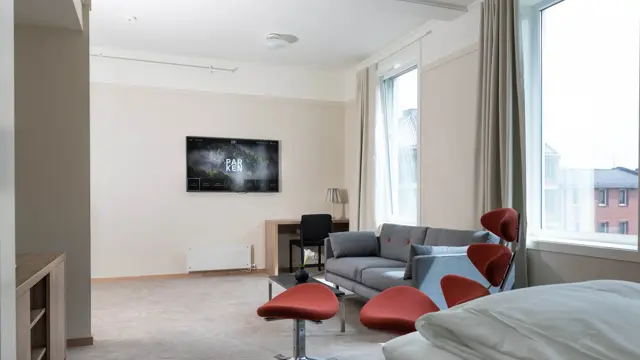 Bilde av sofa, bord og stol ved Tv-en i suiten