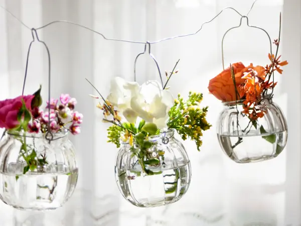 Three hanging glasses with fresh flowers