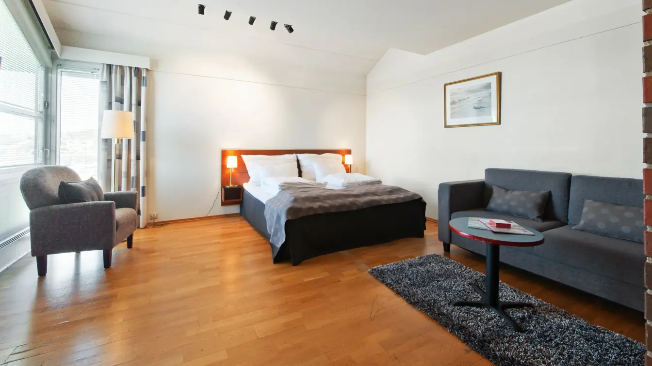 Rom med dobbeltseng, vindu, stol, sofa, tv og skrivebord i Superior Room hos Thon Hotel Sandnes