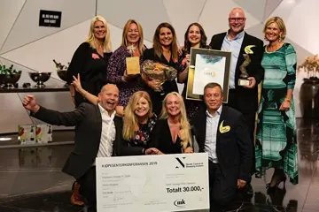 Gruppeabilde av ansatte på AMFI Madla som jubler til kamera mens de holder diplom og stor premiesjekk.