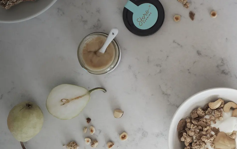 Storohonning, pære og nøtter på marmorbord