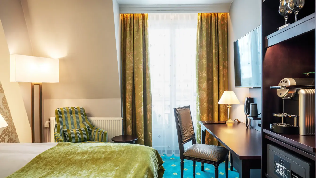 Dobbeltseng, stol, skrivebord og kaffemaskin på dobbeltrom på Hotel Bristol