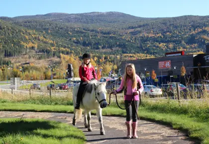 Jenter rir ponni med Bjørneparken kjøpesenter i bakgrunnen