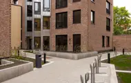 Opparbeidet gårdsrom mellom leilighetsbygg med gangarealer, sykkelparkering og beplantning.