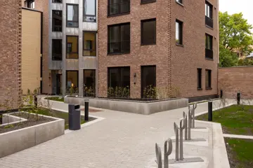 Opparbeidet gårdsrom mellom leilighetsbygg med gangarealer, sykkelparkering og beplantning.