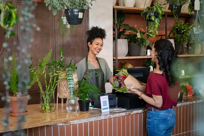 ansatt i blomsterbutikk betjener kunde