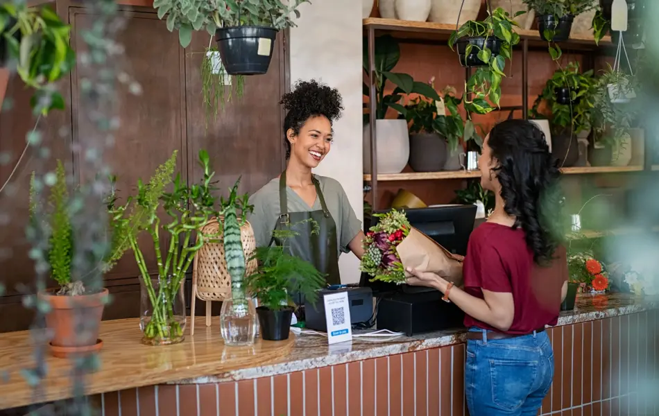 ansatt i blomsterbutikk betjener kunde