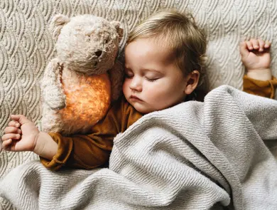 Barn med bamse som sover