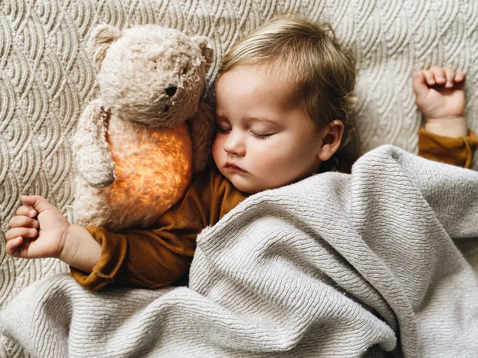 Barn med bamse som sover