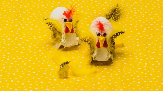 To høner, fylt med hvert sitt egg, laget av eggekartong, filtbiter og fjær på en gulprikkede bakgrunn