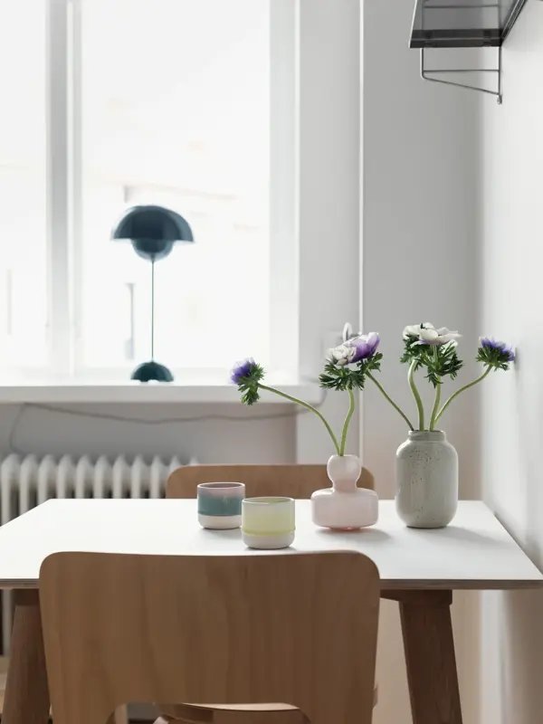 Spisebord med trestoler og mørk blå flowerpotlampe i vinduskarmen 