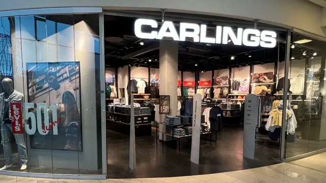 innendørs butikk med sort skilt og hvit tekst og klær