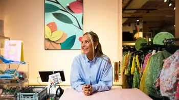 Kaja Sæther, eier av Qomo, står og lener seg på disken til en av butikkene hennes.