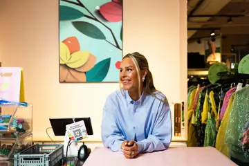 Kaja Sæther, eier av Qomo, står og lener seg på disken til en av butikkene hennes.