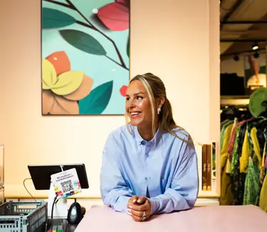 Kaja Sæther, eier av Qomo, står og lener seg på disken til en av butikkene hennes.