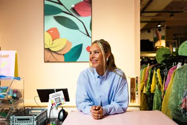 Kaja Sæther, eier av Qomo, står og lener seg på disken til en av butikkene hennes.