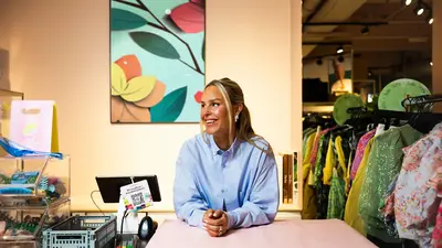 Kaja Sæther, eier av Qomo, står og lener seg på disken til en av butikkene hennes.