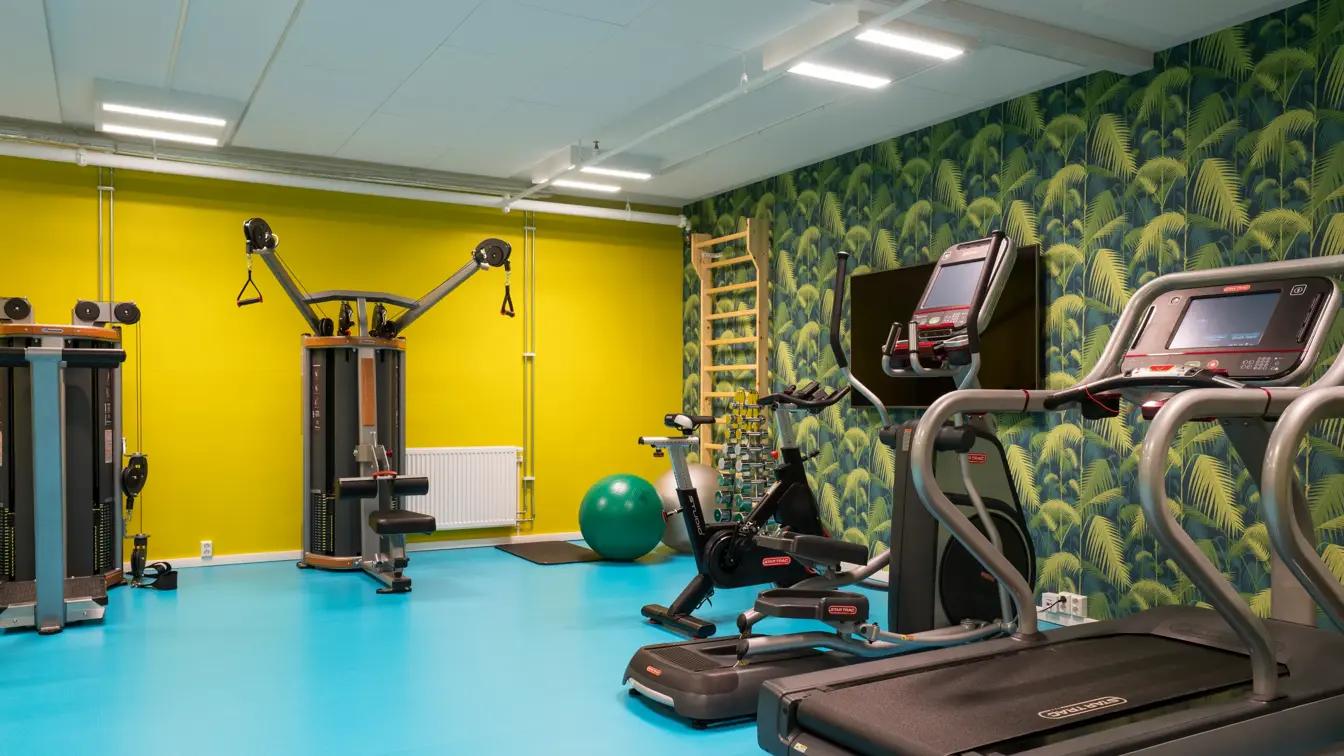 Treningsrom med tredemølle,andre styrkeapparater og jungeltapet og gule vegger på Thon Hotel Gardermoen