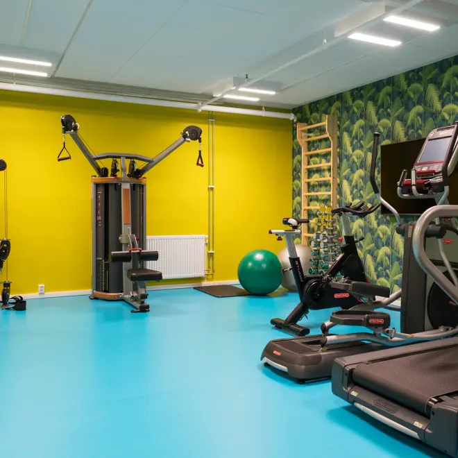 Treningsrom med tredemølle,andre styrkeapparater og jungeltapet og gule vegger på Thon Hotel Gardermoen