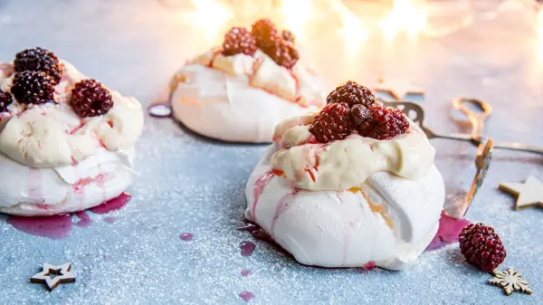 Tre mini pavlovakaker med vanilijesaus og bær på toppen