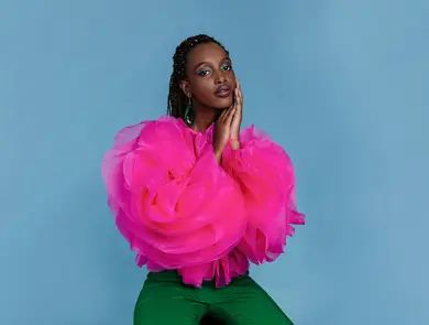 Kvinne i rosa topp foran blå bakgrunn