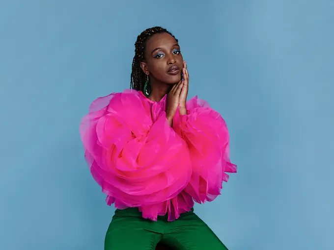 Kvinne i rosa topp foran blå bakgrunn