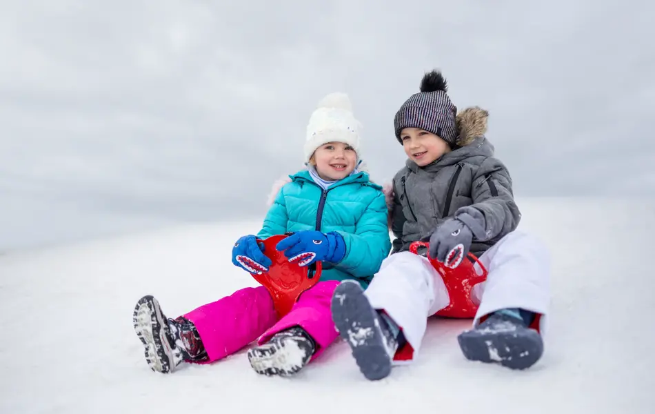 Happy girl and boy slide down on the sliders on the snow