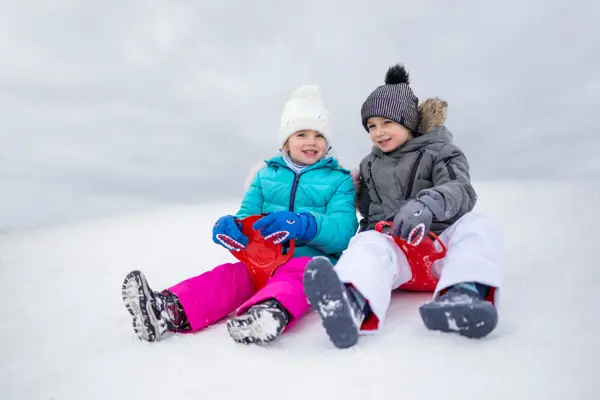 Happy girl and boy slide down on the sliders on the snow