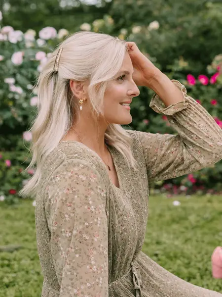 Dame som smiler og sitter på badestranden