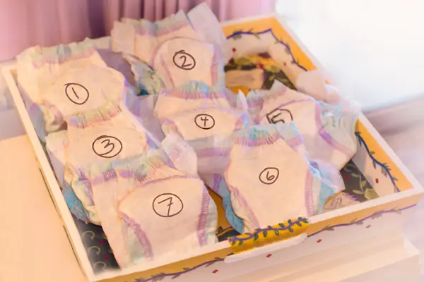 Numbered diapers in a box on a white table.