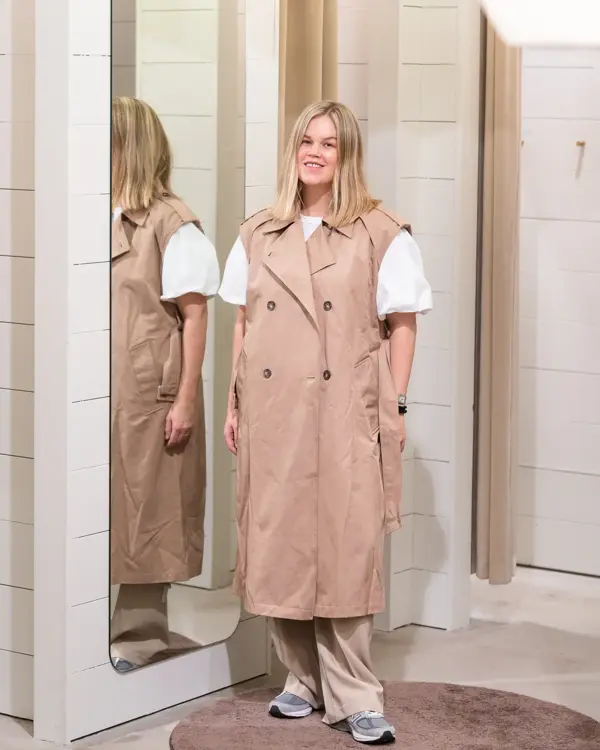 Vårens trender vist av en jente med halvlangt blondt hår. Rosa, 90 tallet og trenchcoat er en del av vårens trender
