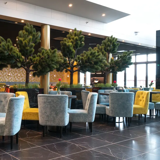 Lobby med planter og trær og sittegrupper på Thon Hotel Nordlys i Bodø sentrum