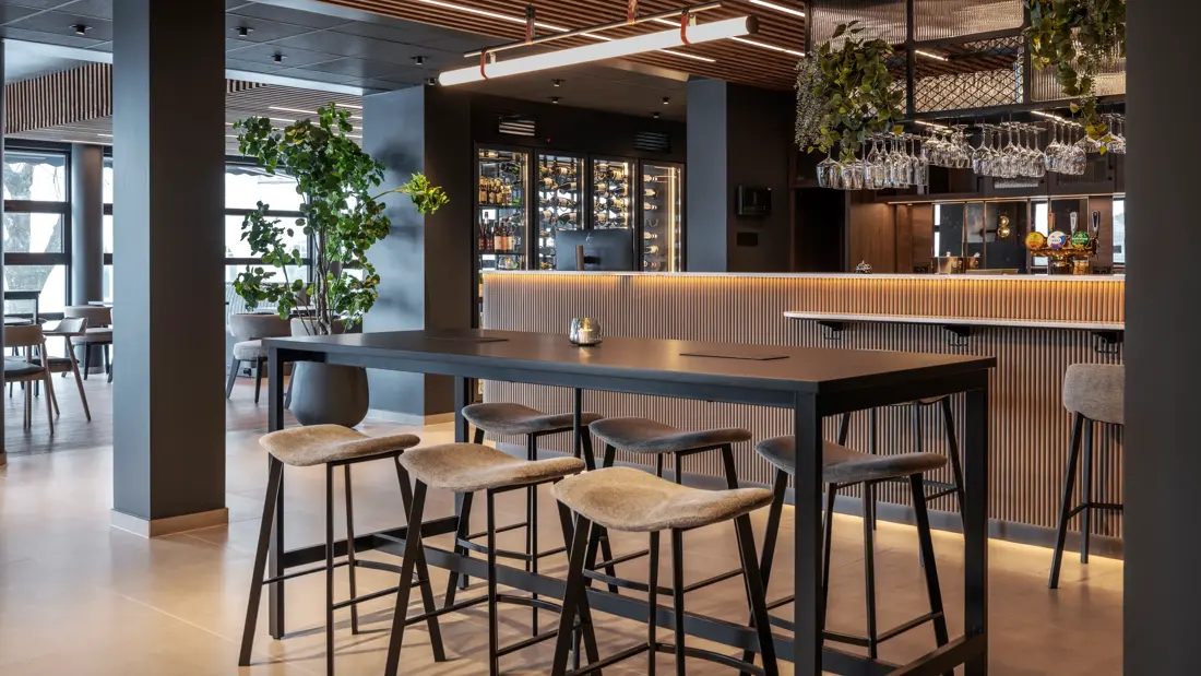 Høybord med stoler i lobby foran resepsjonsdisk.