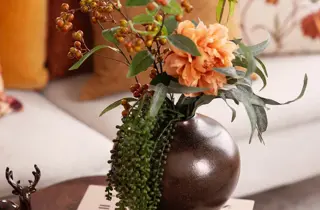 En vase med oransje stilkblomster.