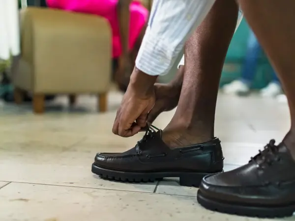 Nærbilde av mannehender som knytter svarte loafers