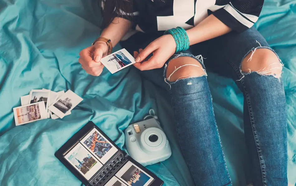 Jente som setter inn polaroidbilder i et album