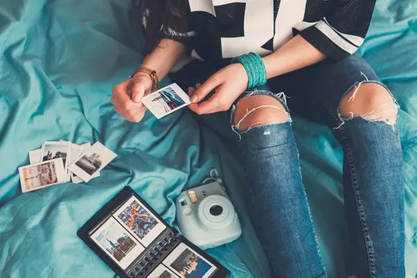 Jente som setter inn polaroidbilder i et album