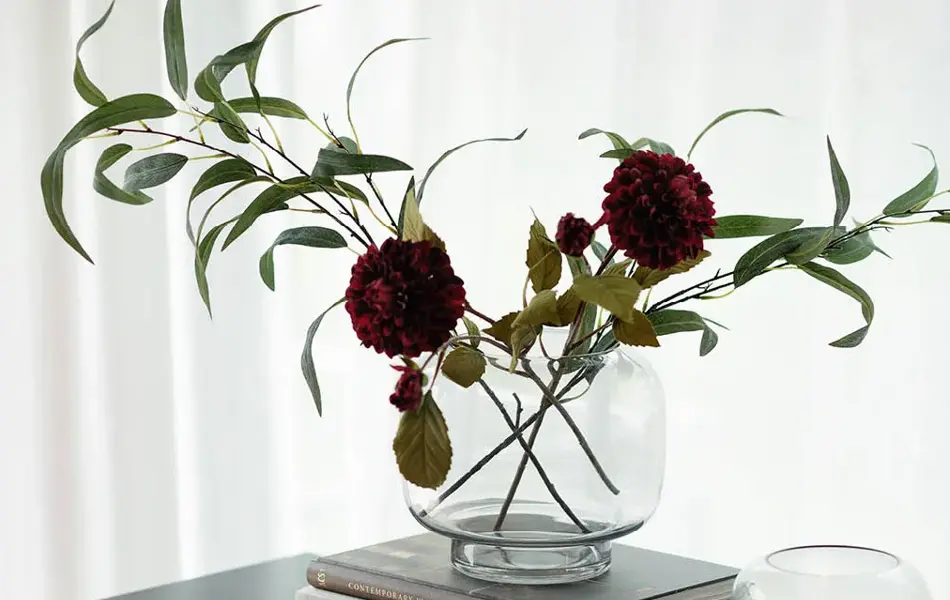 Konsollbord med trekrukk, telysholder og en vase med blomster på tre bøker.