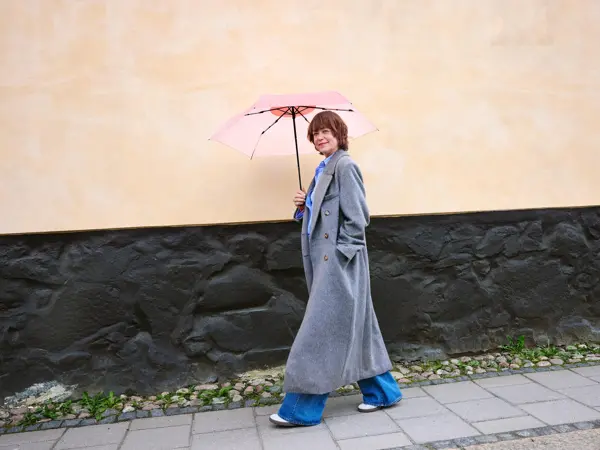 Dame går ute med Rosa sløyfe paraply fra Lindex