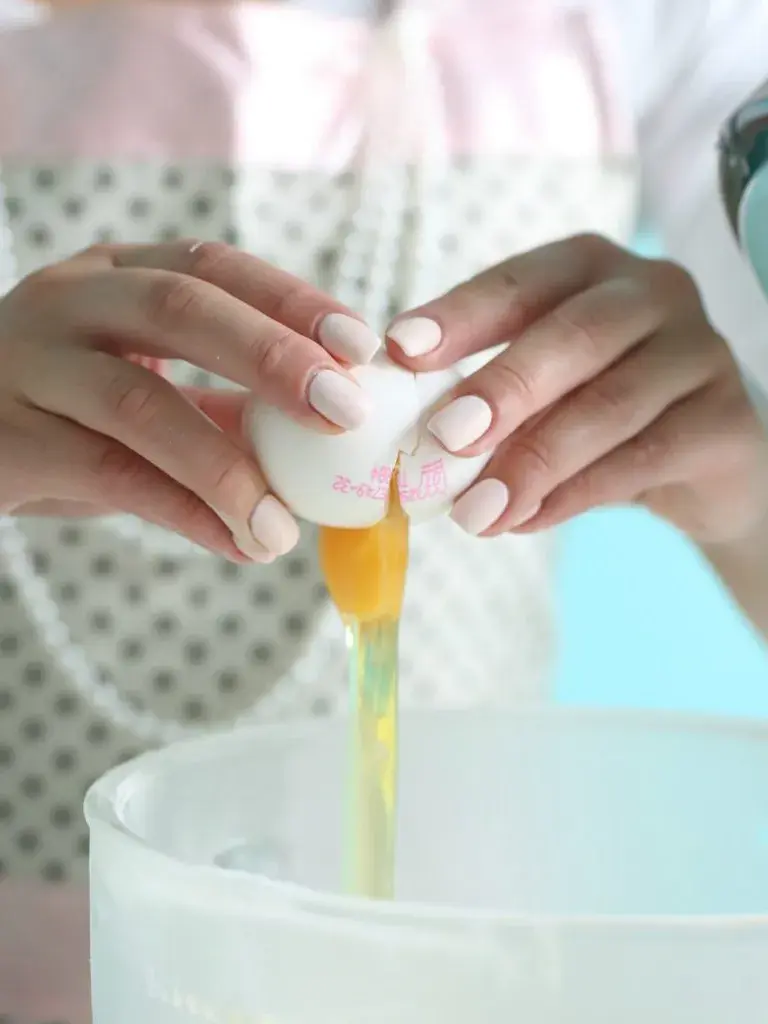 hender som knekker et egg over en bakebolle