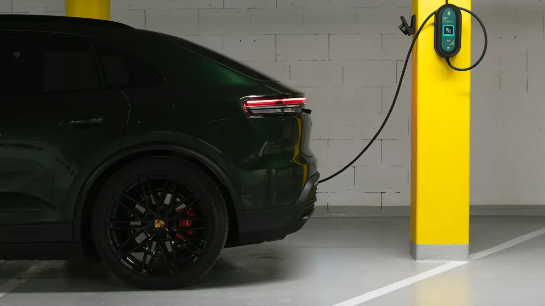 En mørk el-bil står i en garasje og lader. 