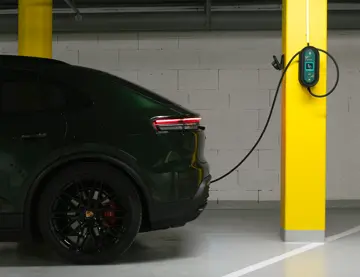 En mørk el-bil står i en garasje og lader. 