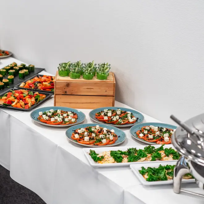 Selskapsbuffé med tapasmat på langbord dekket med hvit duk.