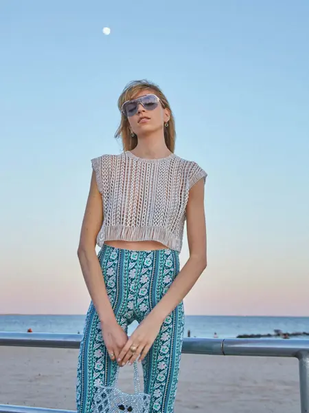 Dame med mønstrete bukse og heklet sølvtopp ser i kamera 