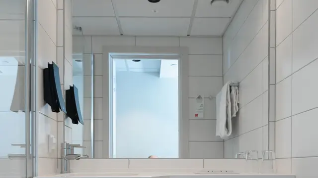 Bad med hvite fliser, stort speil og vegghengt toalett.  I standard dobbelt rom på Thon Hotel Norge i Kristiansand.