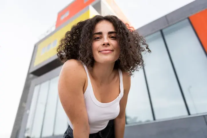Smiling woman with curly hair in front of building
