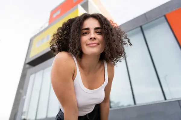 Smiling woman with curly hair in front of building