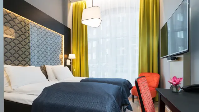 Dobbeltseng, skrivepult, stol, tv, og blomst  på Standard room twin på Thon Hotel Spectrum i Oslo sentrum