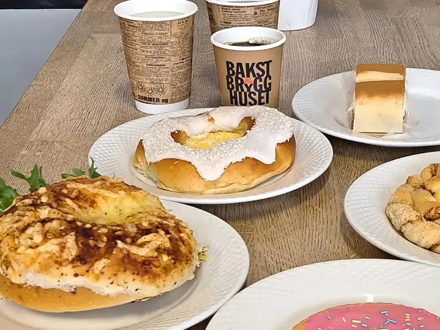 Hvite tallerkener med bakevarer og hvite og bruke kaffekopper