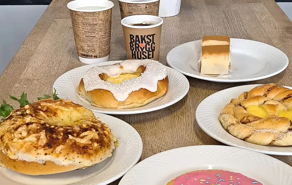 Hvite tallerkener med bakevarer og hvite og bruke kaffekopper